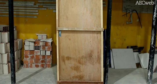 Porta de madeira e batente sem pintura, em ambiente com outros materiais de construção